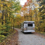 Shot of the back of an RV driving through fall foliage