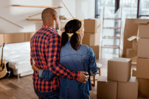 rear view of couple looking at new home with cardboard boxes